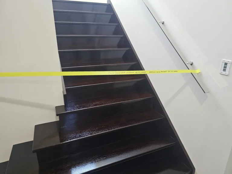 Staircase with freshly stained dark timber treads, taped off while the finish cures