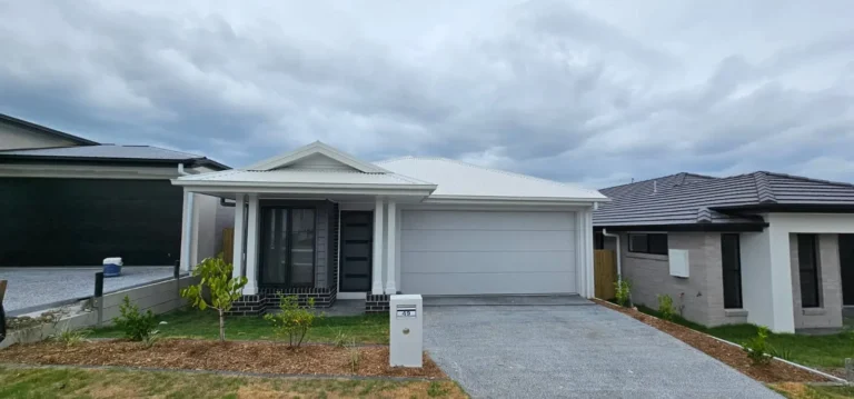 Newly painted single-storey home with white render and charcoal garage door