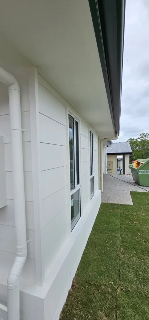 Smooth white painted exterior wall and window trim, close-up